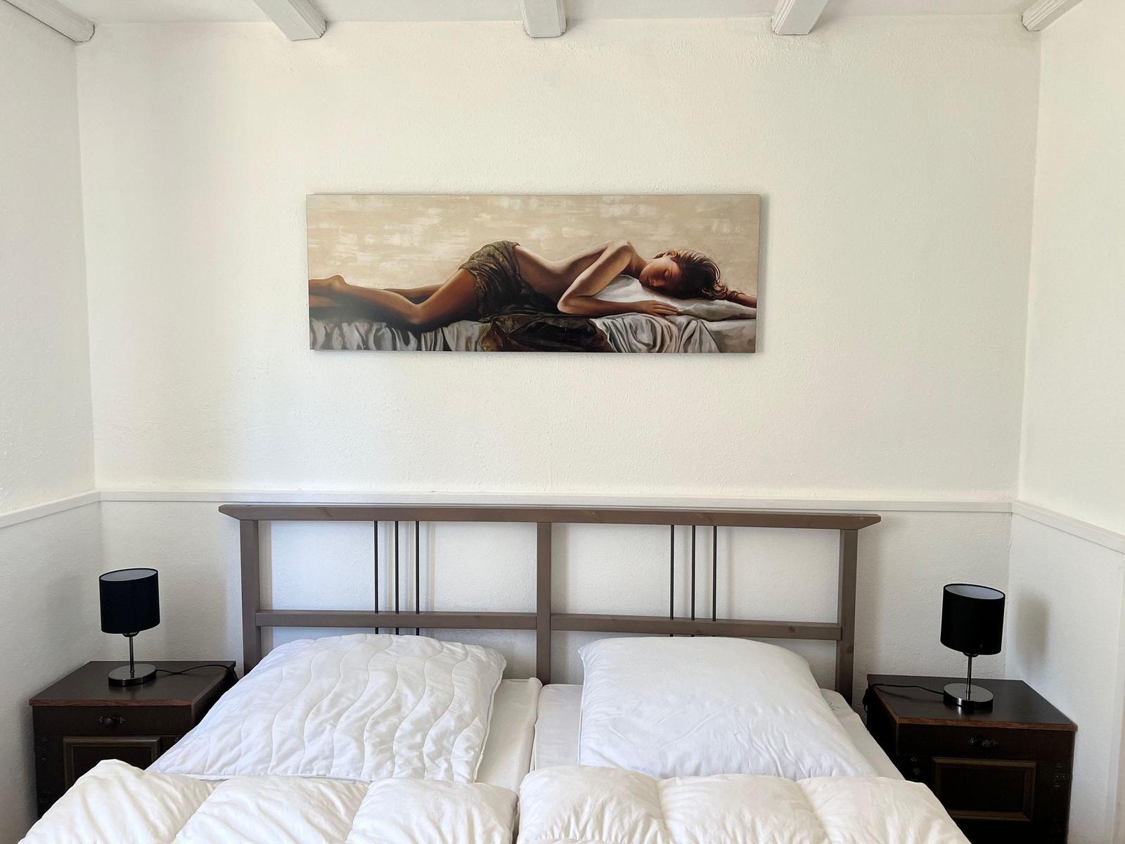 Bedroom with bed, nightstands, and wall art.