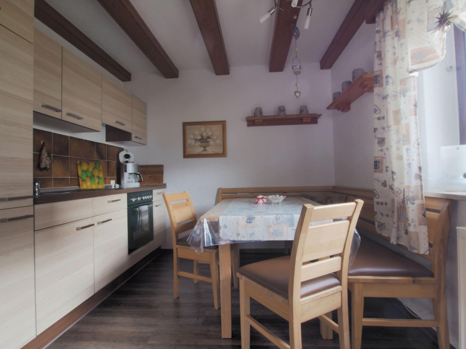 Kitchen with dining table, wooden chairs, and beams on the ceiling.