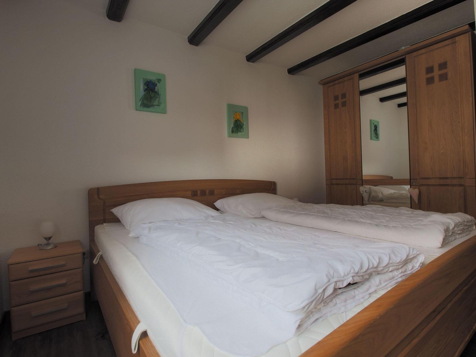 Bedroom with wooden bed, wardrobe, and nightstand.