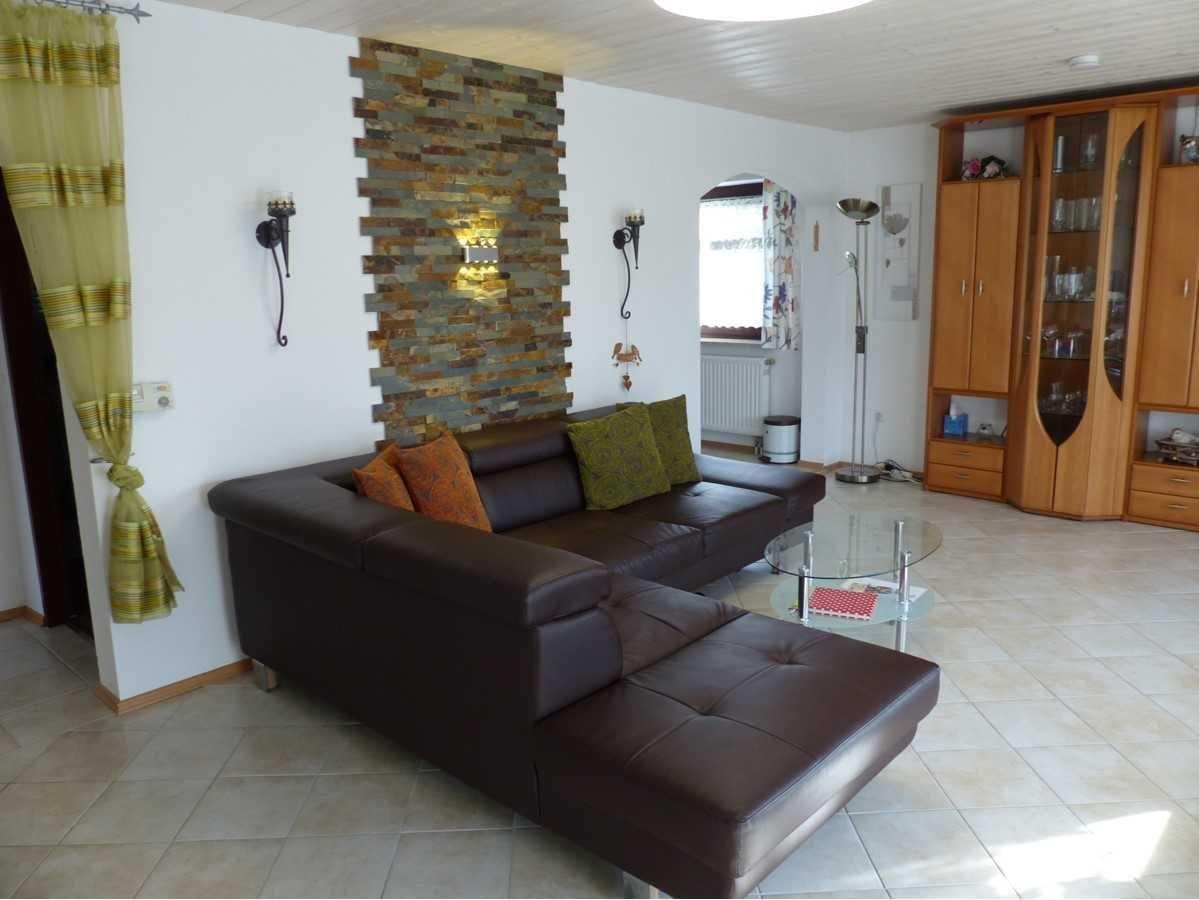 A living room with brown sofa, glass table, and wooden cabinet.