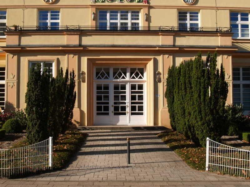 Eingangsbereich mit Treppe, weißen Türen und hohen Zypressen.