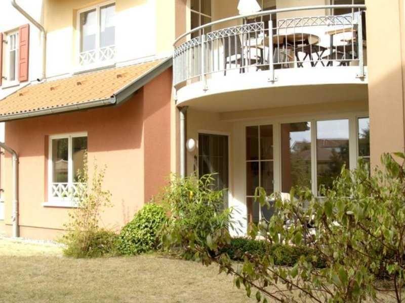 Haus mit Balkon, Terrasse und Garten. Fenster und Türen sind sichtbar.