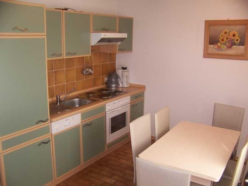 Kitchen with dining area, green cabinets, and brown tiles