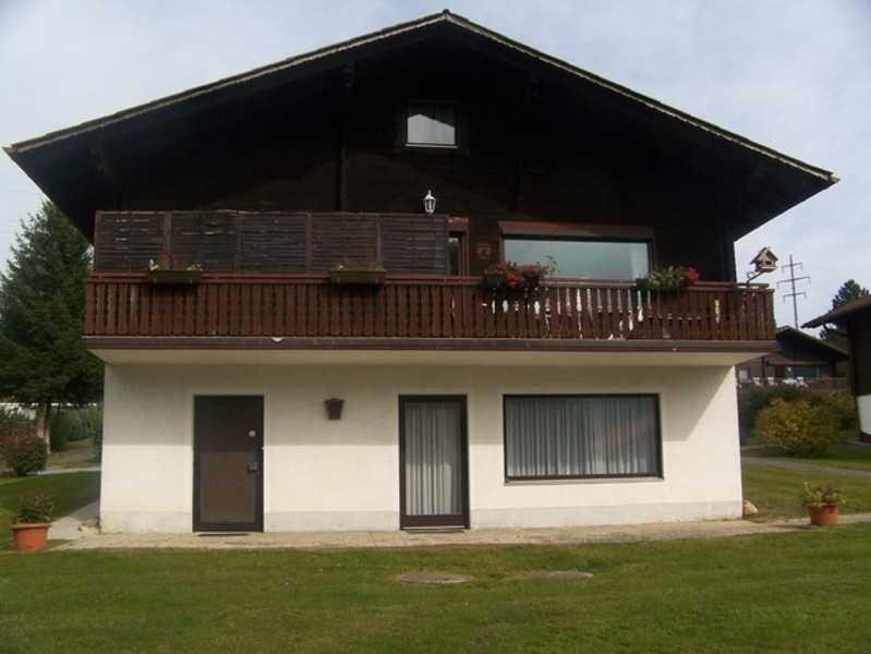A two-story house with a balcony and windows. Lawn in front of the house.