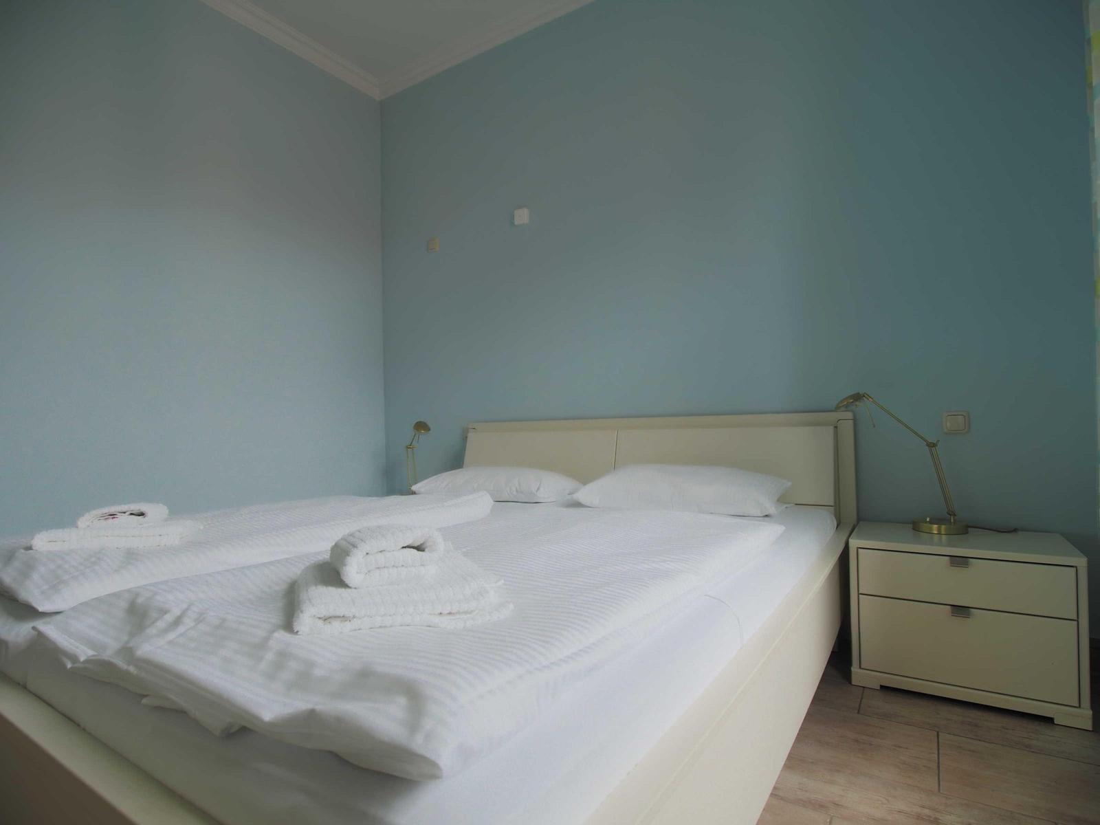 Schlafzimmer mit Bett, Nachttisch und Lampen an den Wänden.