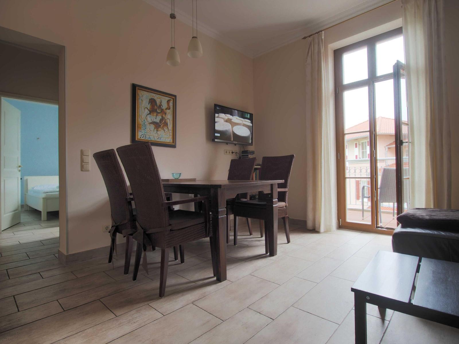 Esszimmer mit Tisch, Stühlen und TV. Durchgang zur Schlafzimmer. Terrasse mit Blick.