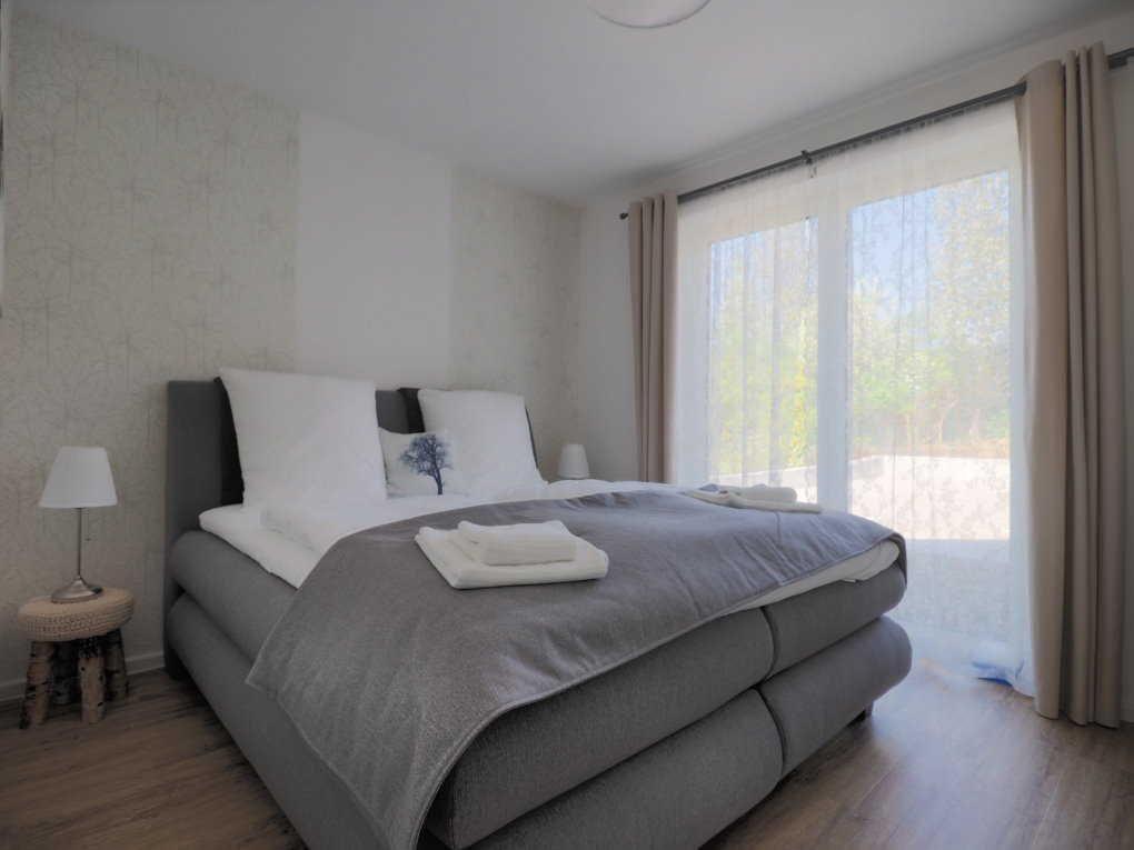 Schlafzimmer mit großem Bett, Fenster und Holzboden.