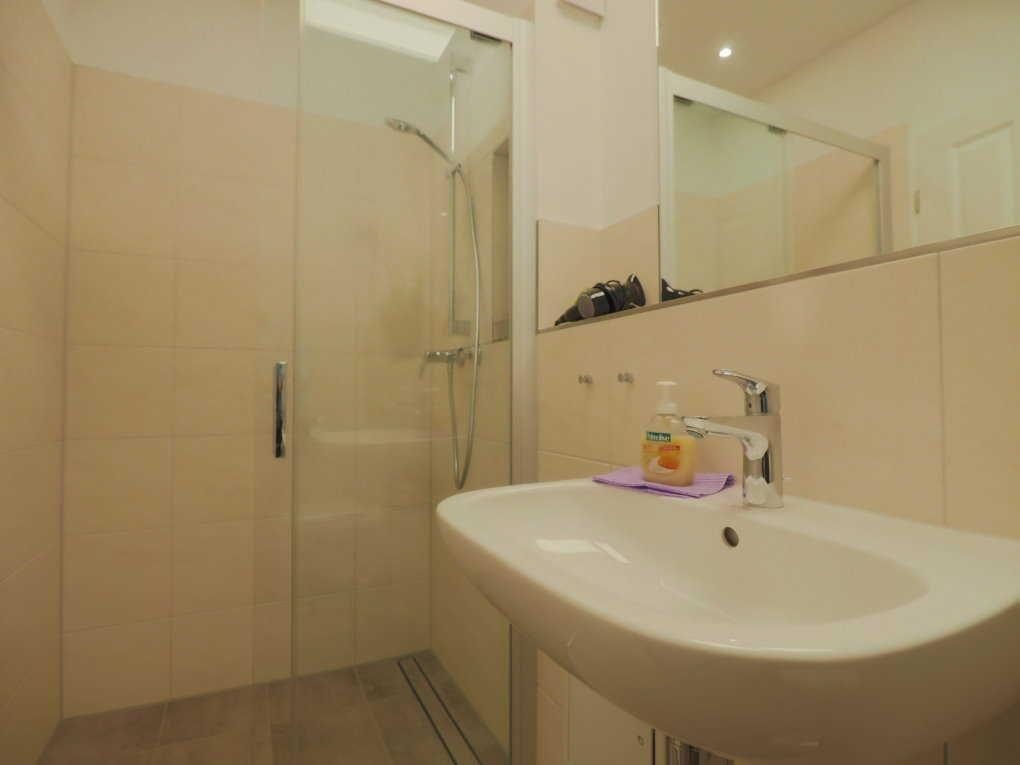 Bad mit Dusche, Waschbecken und Spiegel