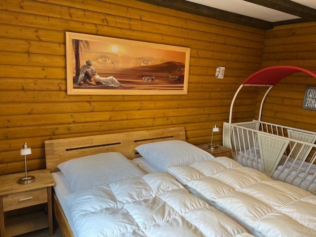 Bedroom with wooden walls, bed, nightstand, and crib.
