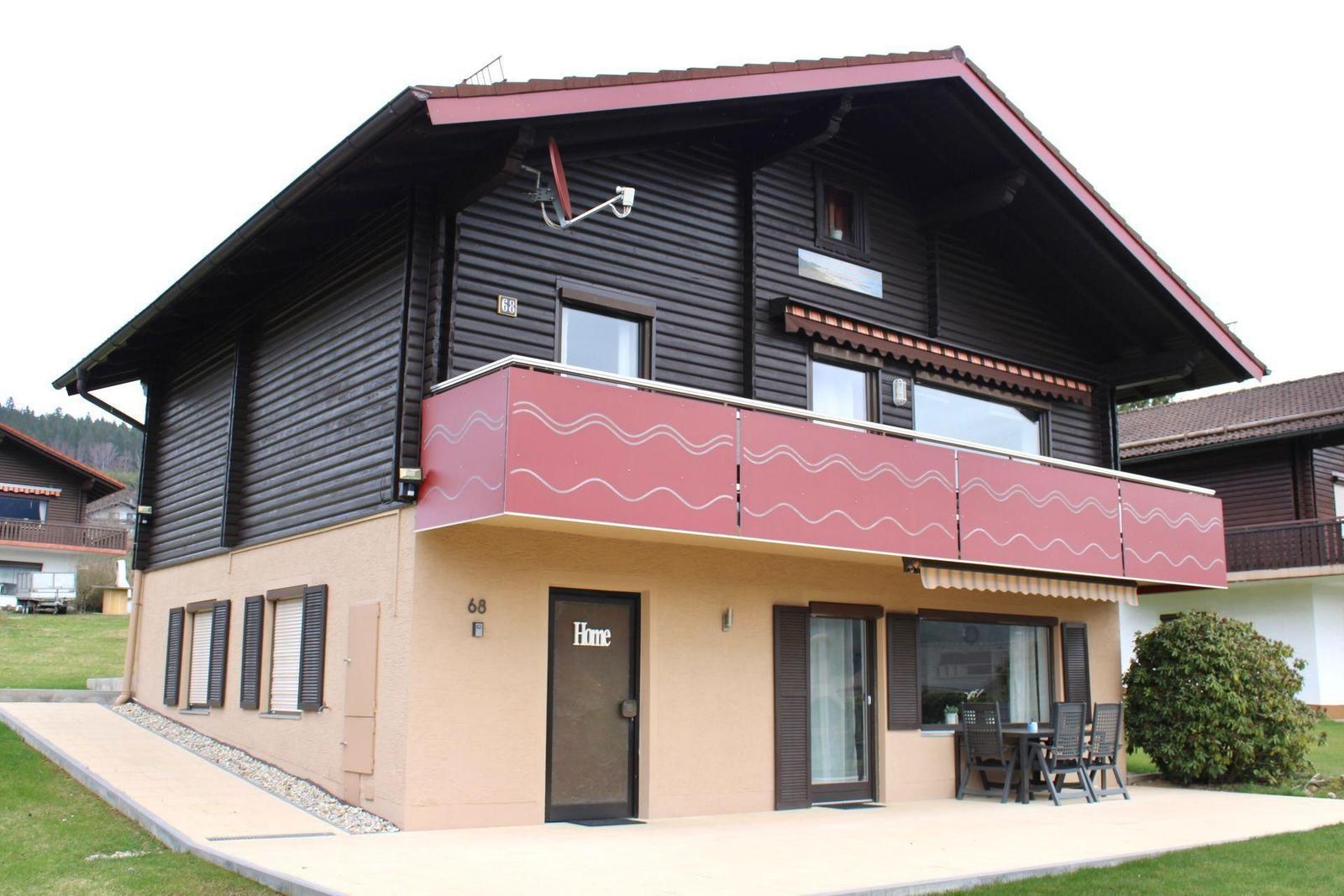 Two-story holiday home with balcony, terrace, and entrance door. House number 68.