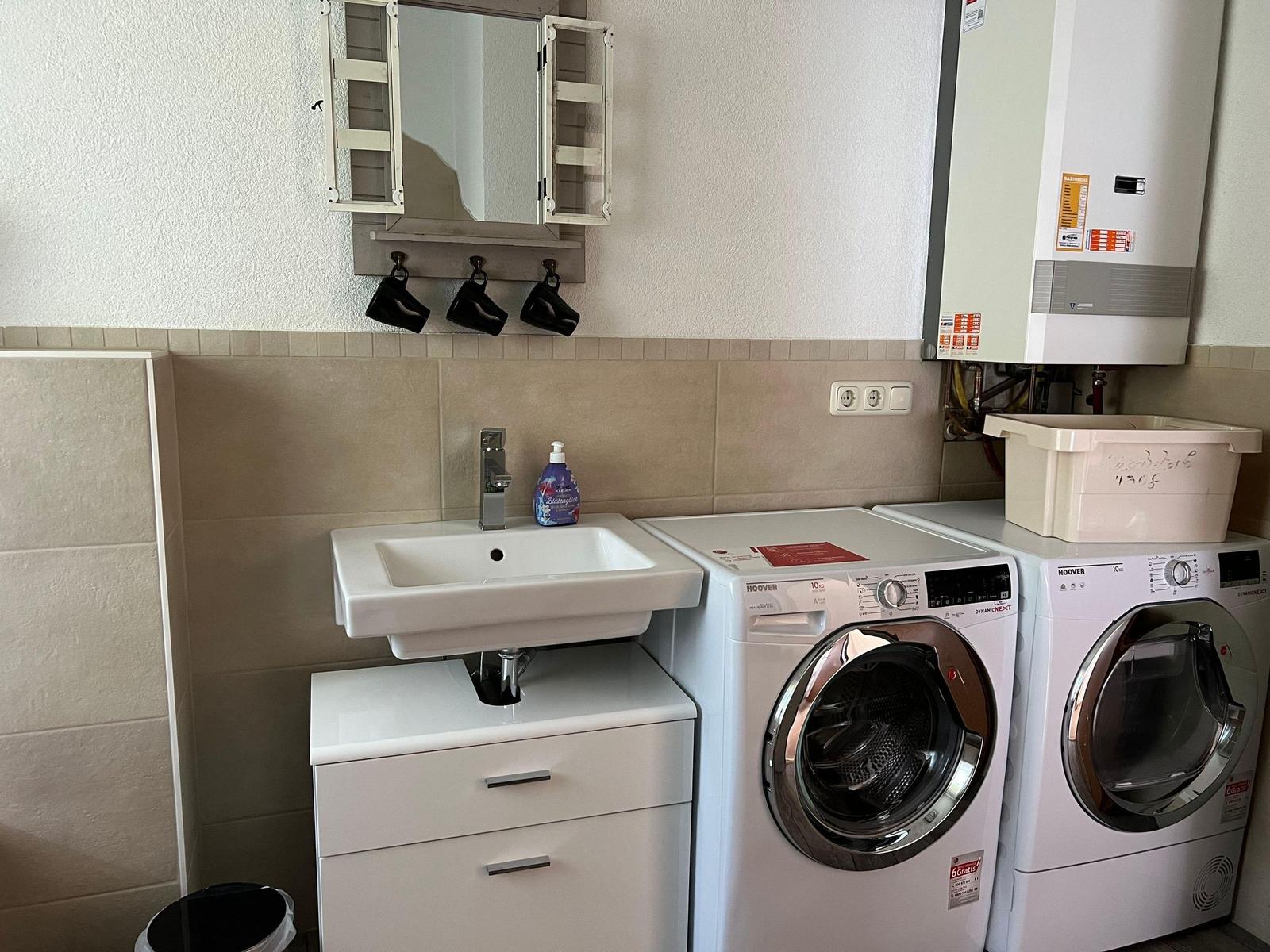 Washing machine and dryer are next to sink with mirror cabinet.