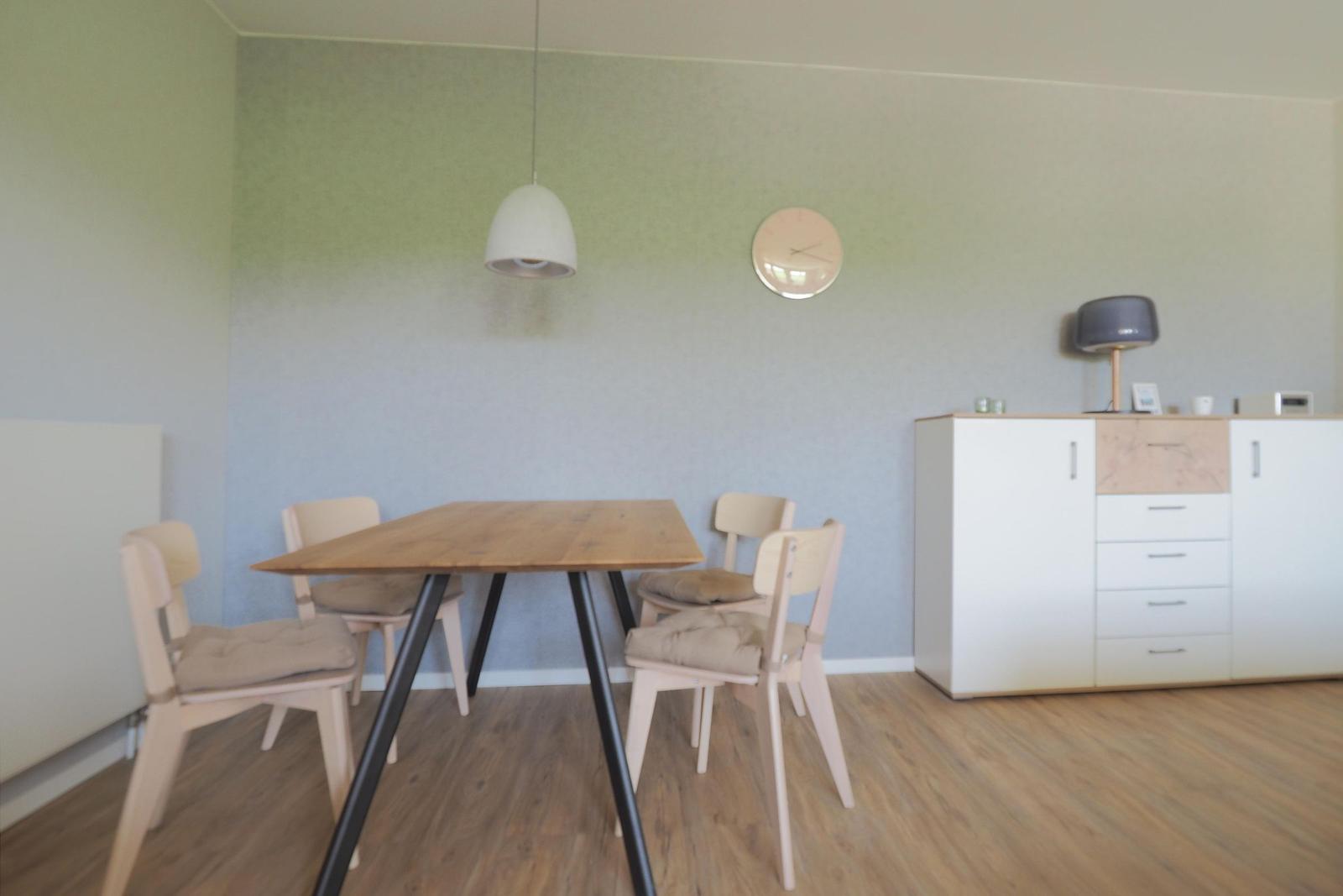Essbereich mit Holztisch, vier Stühlen und Sideboard an der Wand.