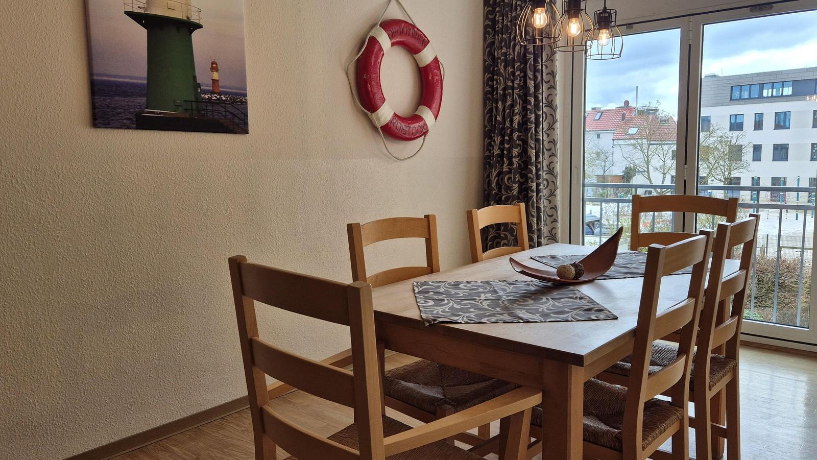 Esszimmer mit Holztisch, Stühlen und Fensterblick auf Balkon