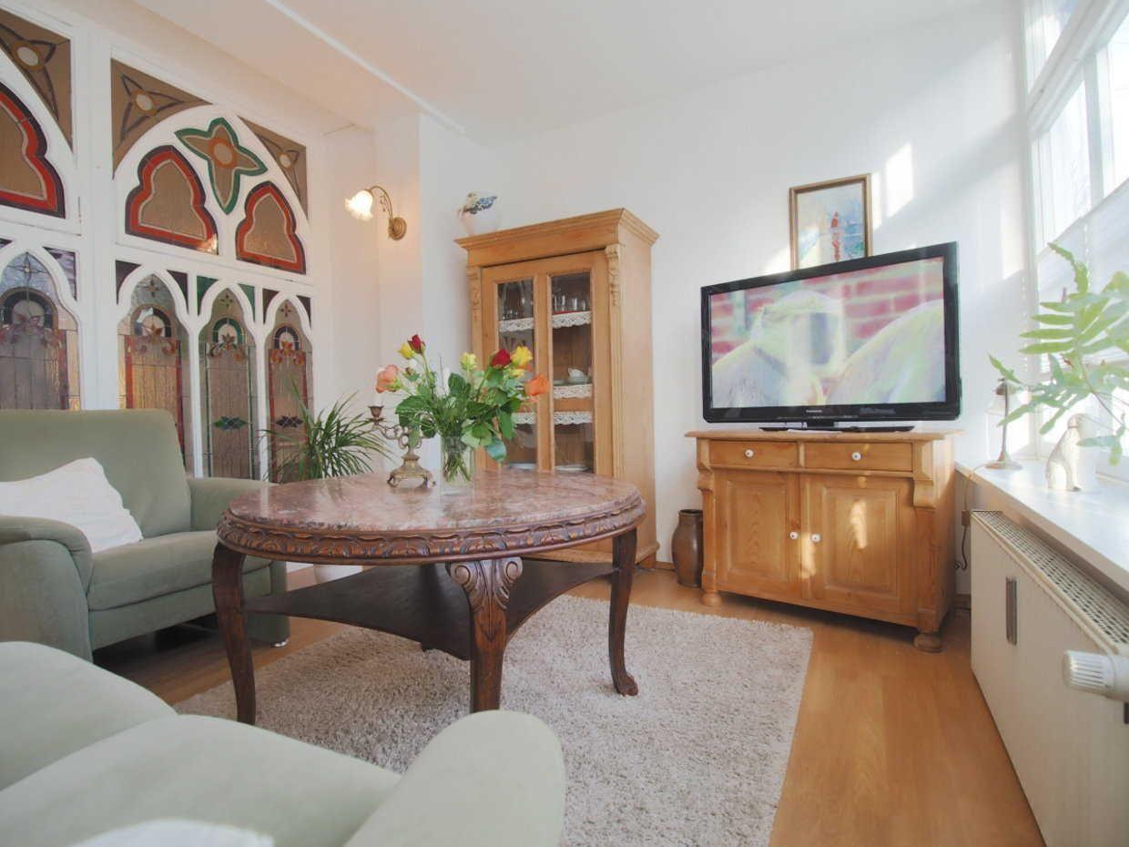 Wohnzimmer mit Holzmöbeln, TV, Couch und dekorativen Wandverkleidungen.