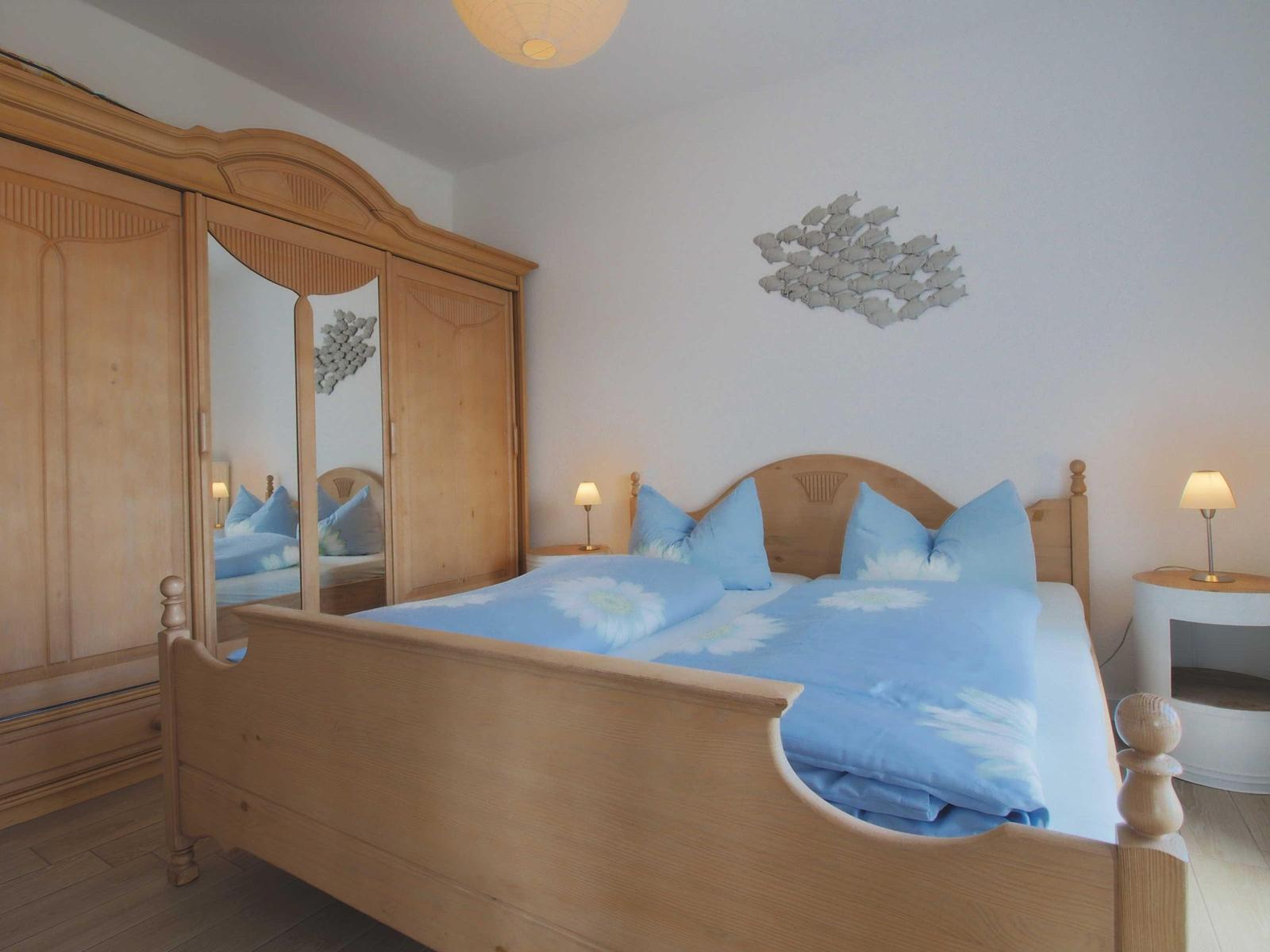 Schlafzimmer mit Holzbett, Kleiderschrank und Wanddekoration.