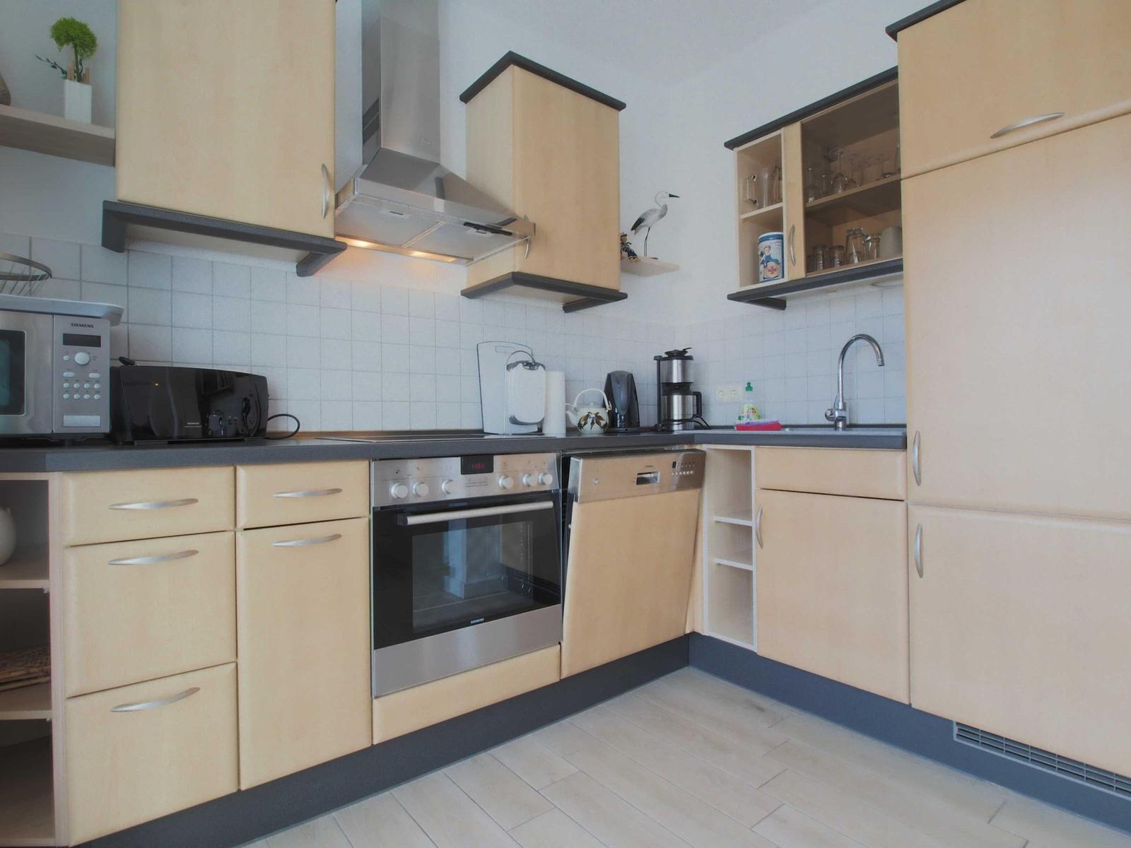 Küche mit Holzschränken, Edelstahlgeräten und Arbeitsfläche.