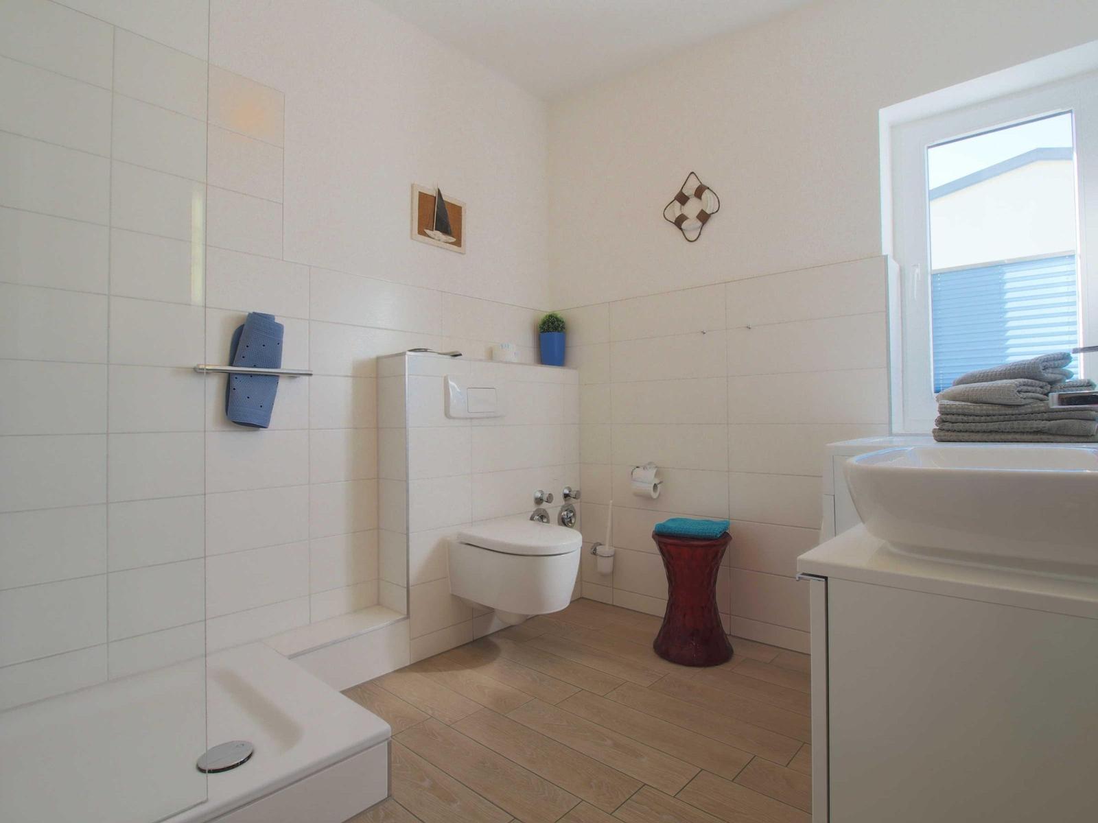Bad mit Dusche, Toilette und Waschbecken. Fenster, Handtuchhalter und dekorative Elemente.