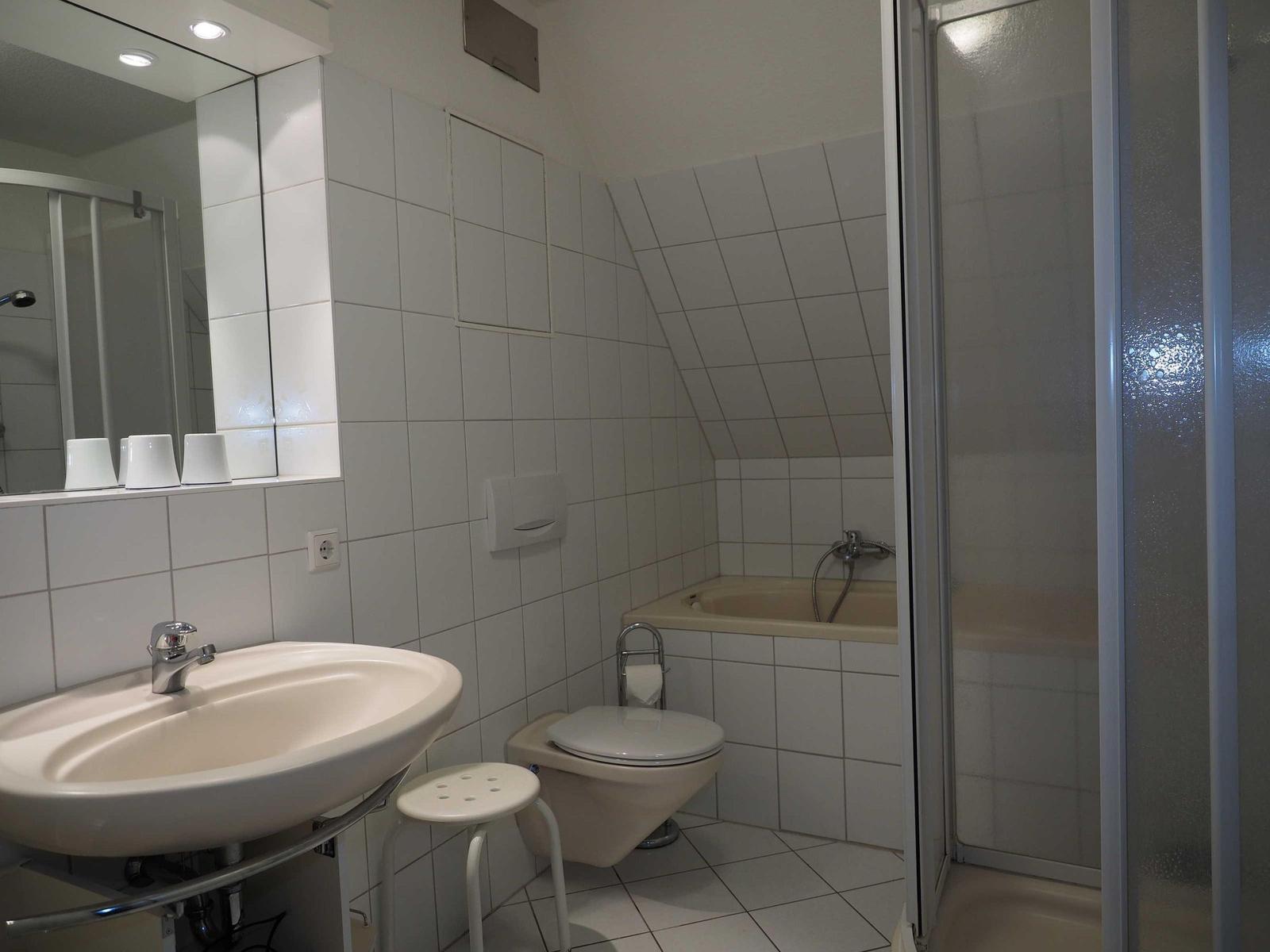 Badezimmer mit Dusche, Badewanne, Toilette und Waschbecken.
