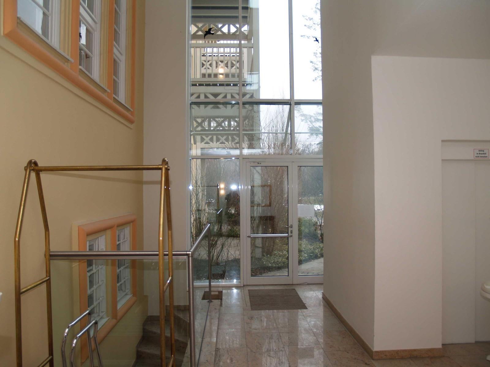 Haus mit Eingangsbereich, Glaswand und Treppe mit Metallgeländer.