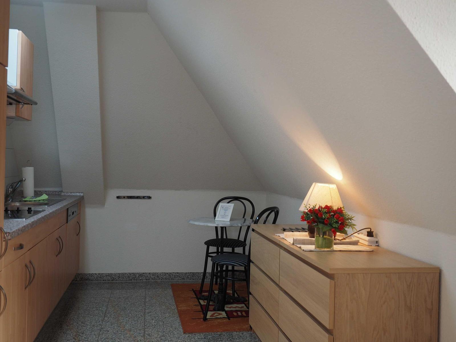 Küche mit Esstisch, Schrank und Lampe unter Dachschrägen.