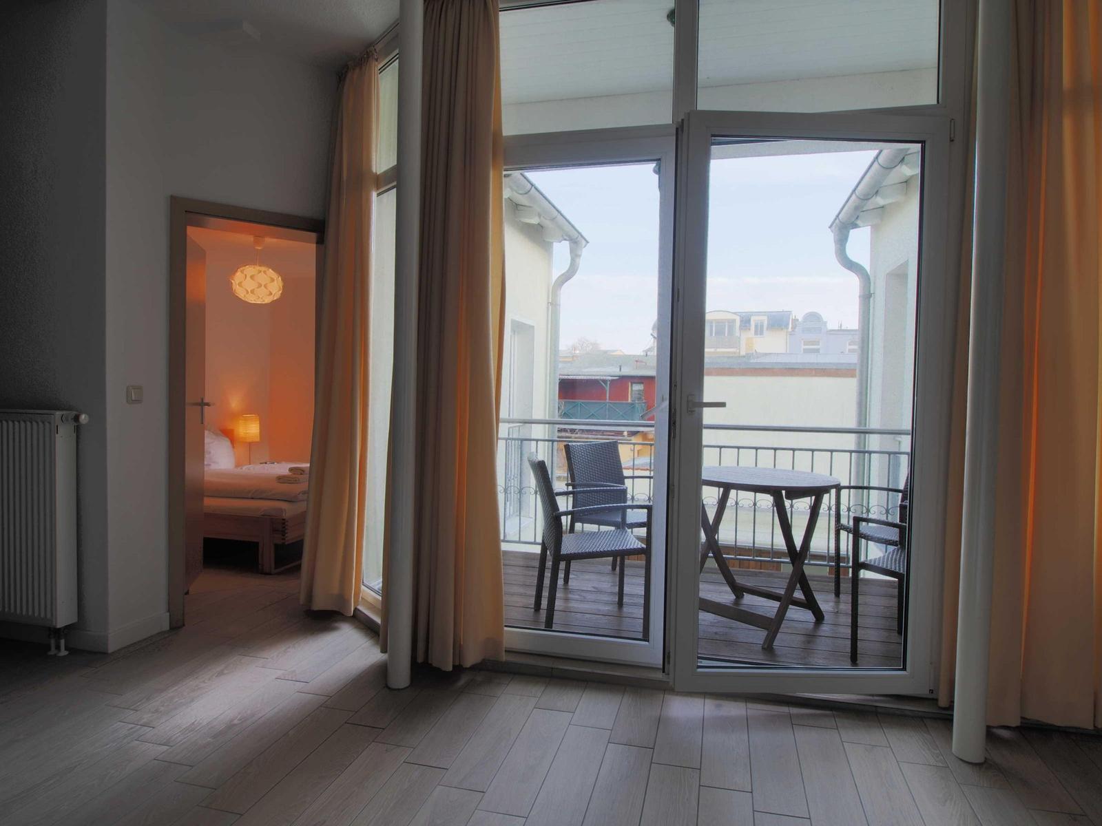 Wohnraum mit Balkon, Tisch und Stühlen. Durchgang zur Schlafzimmer.