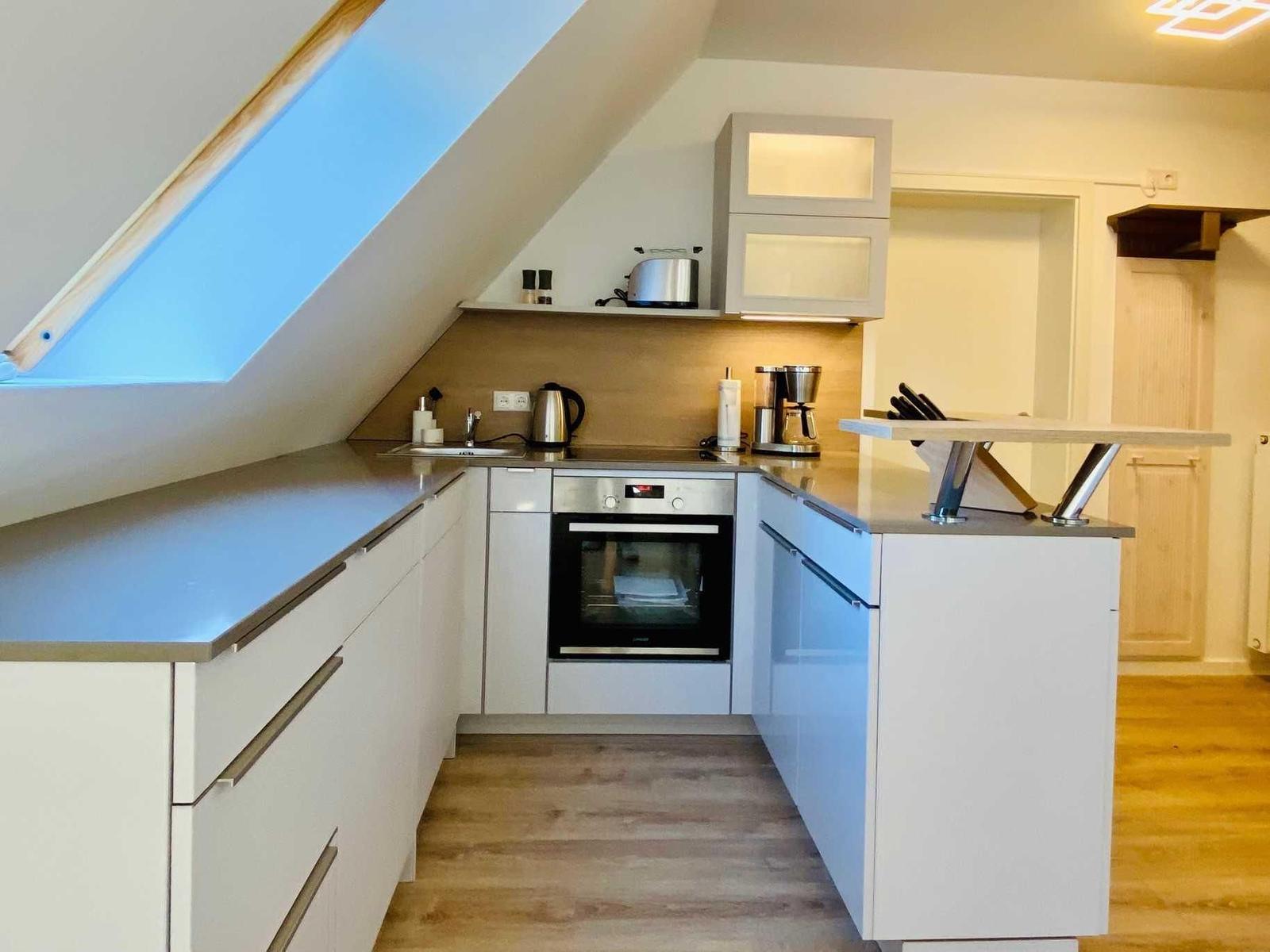 Küche mit Dunstabzug, Herd und Kühlschrank unter Dachschrägen.