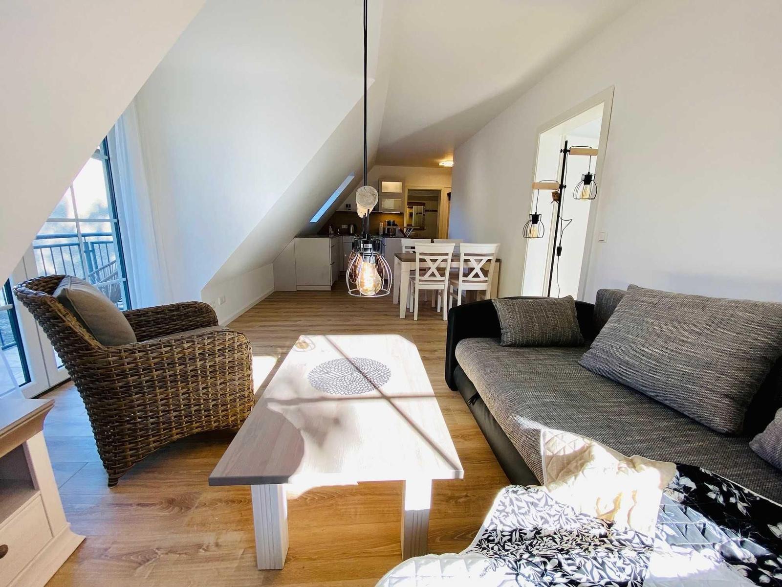 Wohnbereich mit Sofa, Esstisch und Blick auf Balkon