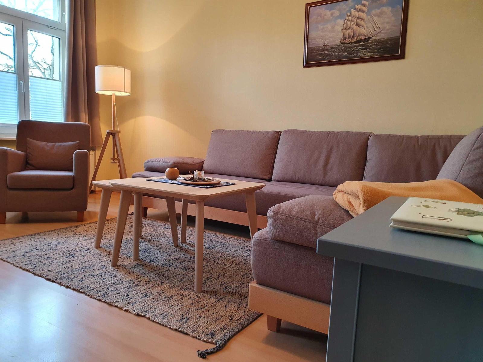 Wohnzimmer mit Sofa, Sessel, Tisch und Wandbild.