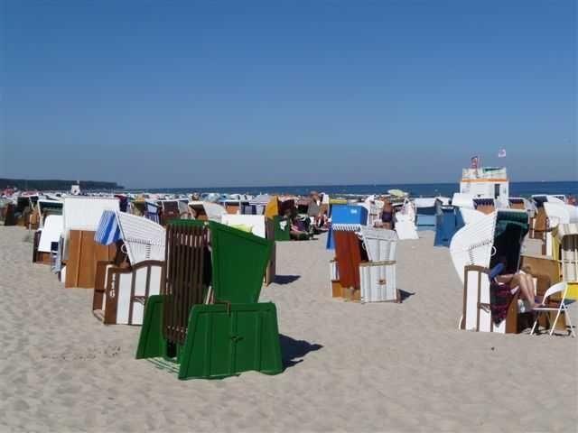 Strand mit vielen Liegestühlen und Blick auf das Meer unter blauem Himmel.