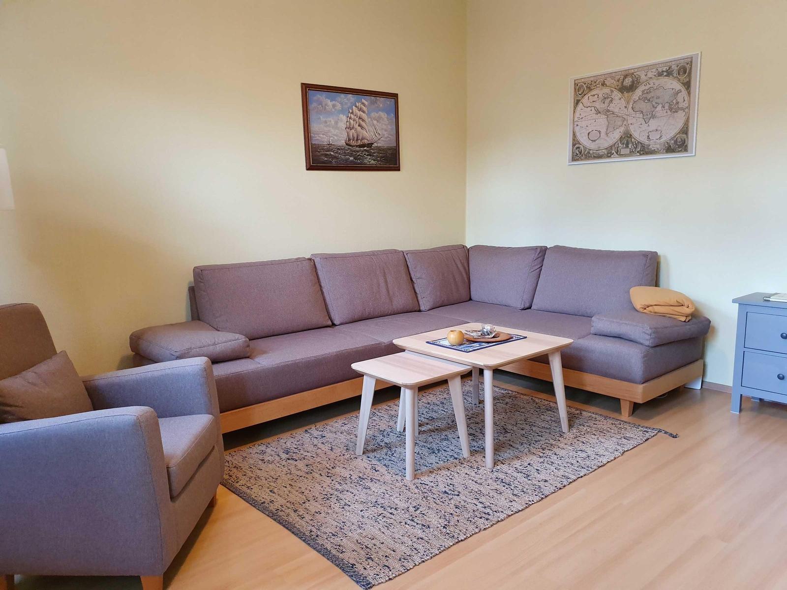 Ein Wohnzimmer mit grauem Sofa, Holztisch und Teppich auf Holzboden.
