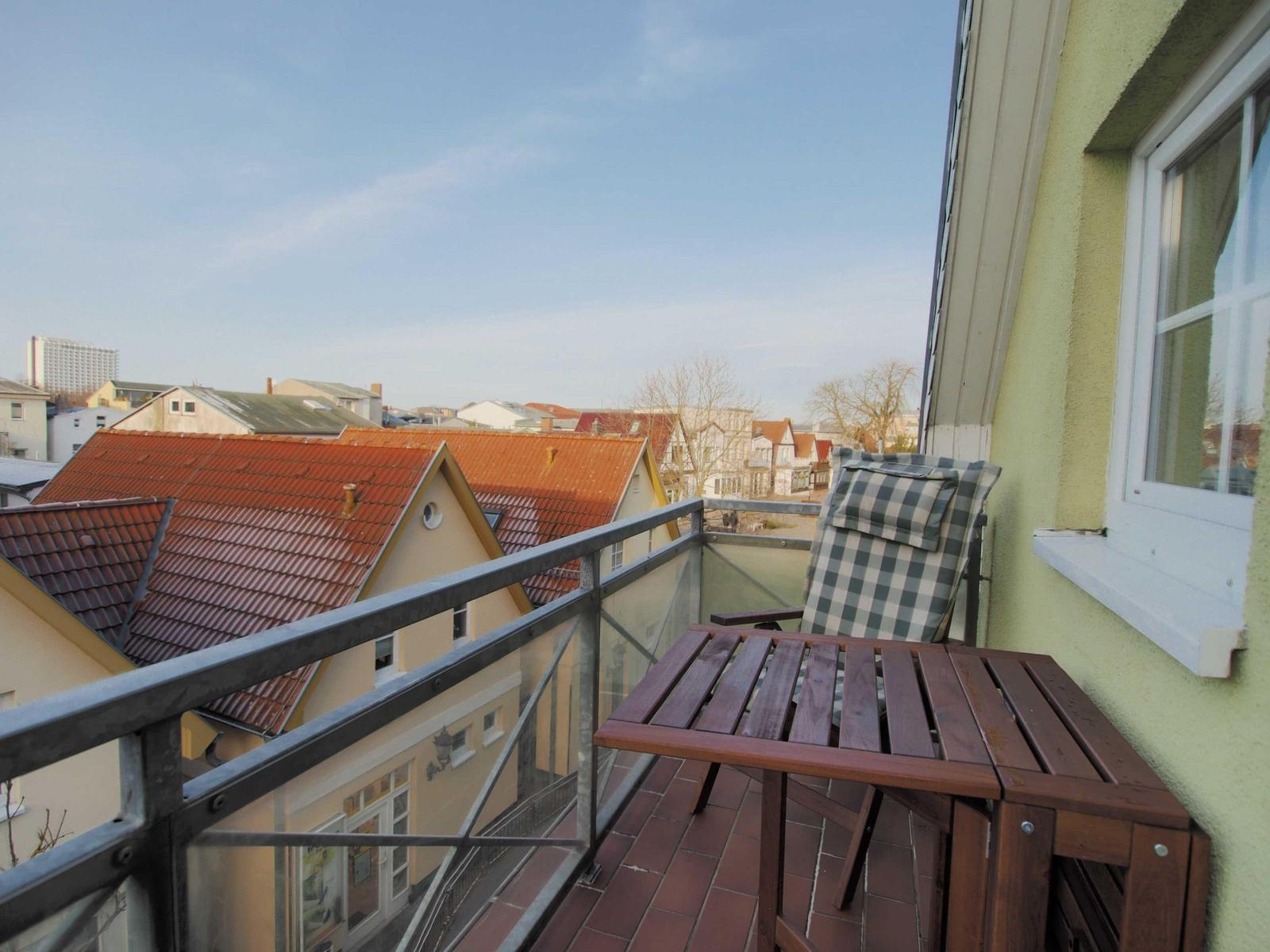 Terrasse mit Tisch und Stuhl, Blick auf Dächer und Straße.