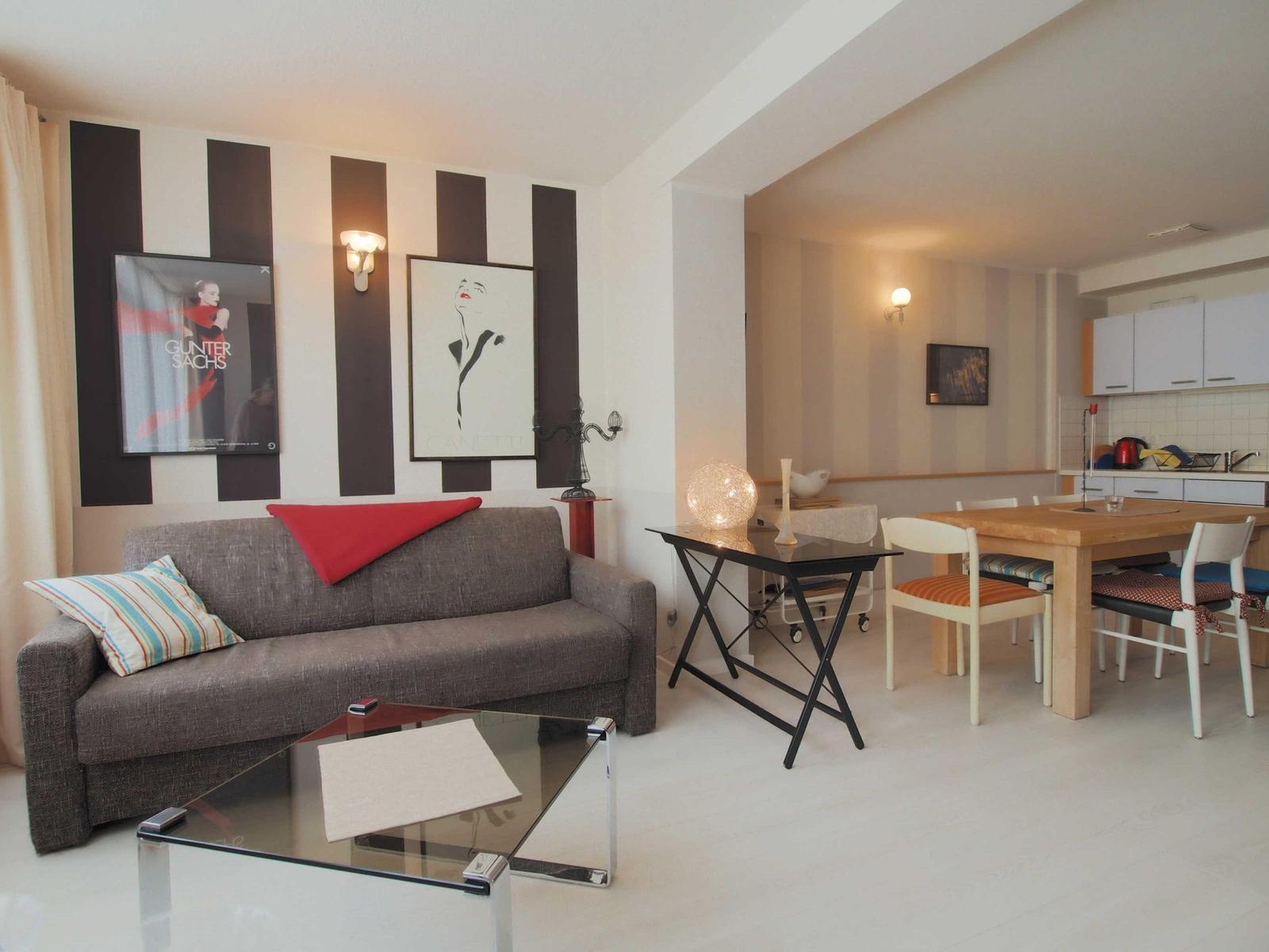 Wohn- und Essbereich mit Sofa, Esstisch und Küche im Hintergrund.