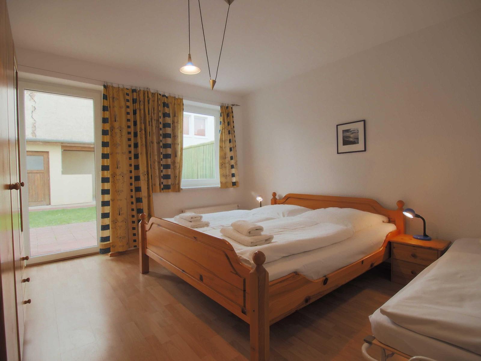 Schlafzimmer mit Doppelbett, kleinem Bett und Blick auf den Hof.