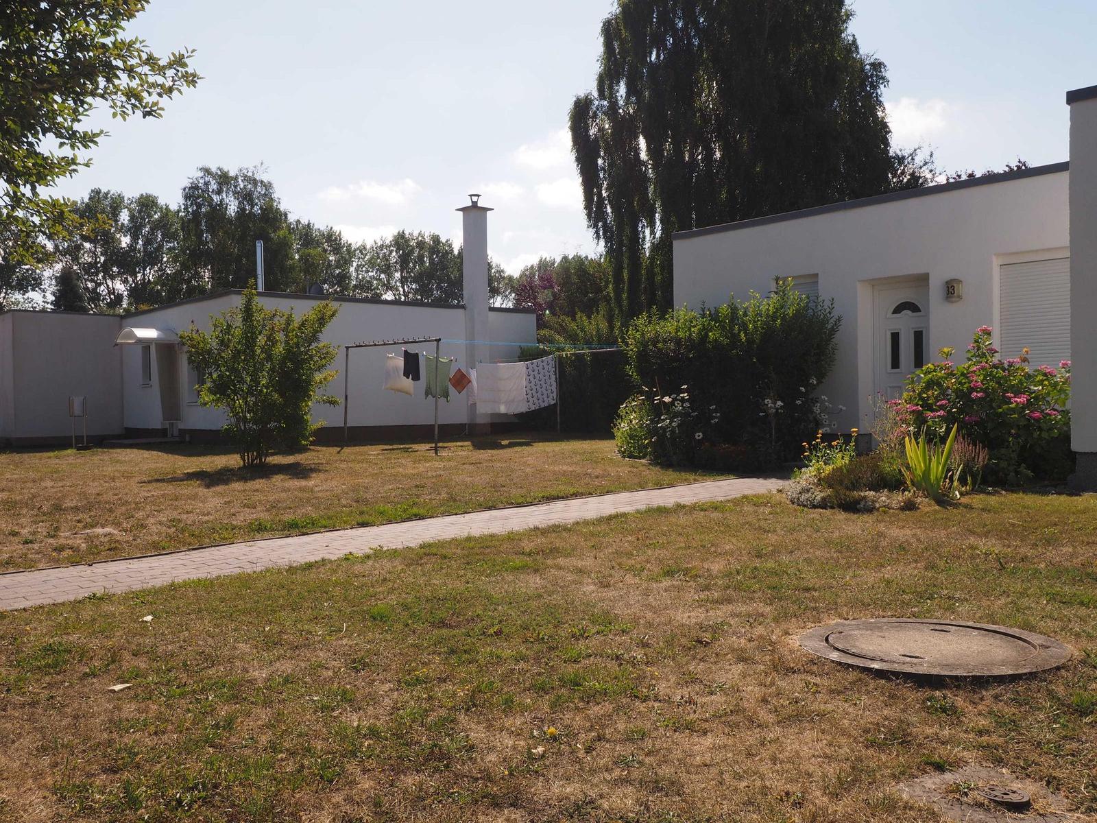 Haus mit Garten, Waschleine und Blumenbeet. Pfad führt zur Eingangstür.