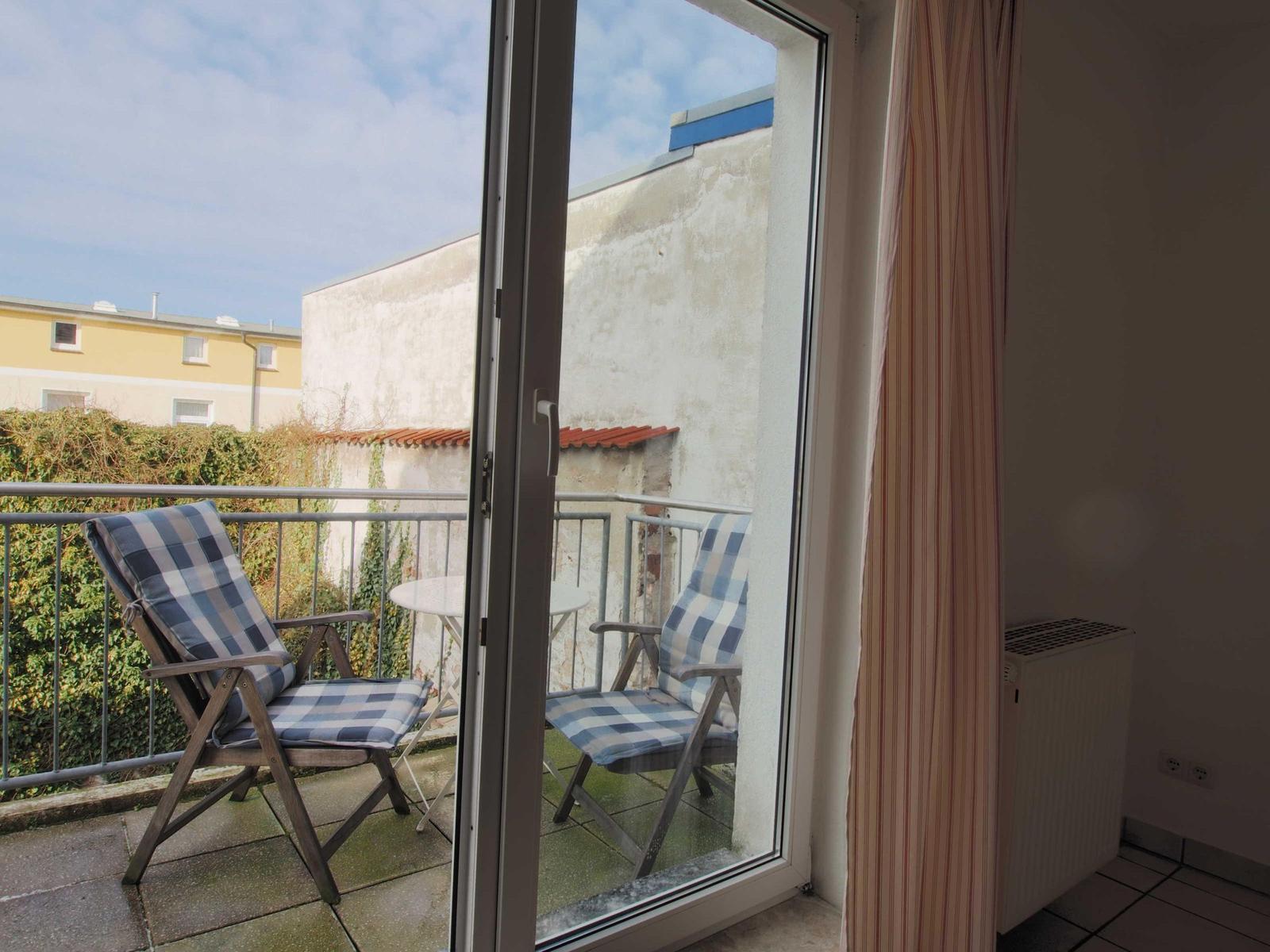 Terrasse mit zwei Stühlen und Tisch. Blick auf Wohnhaus und Hedges.
