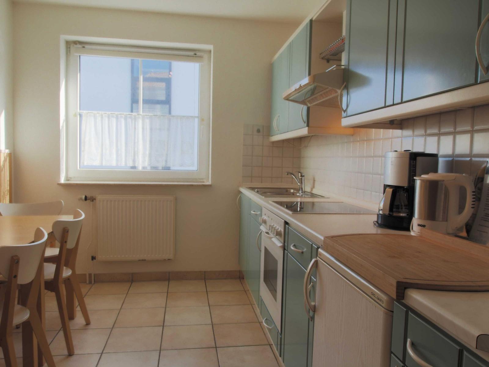 Küche mit Essbereich, Fenster, Arbeitsplatte und Küchengeräten.