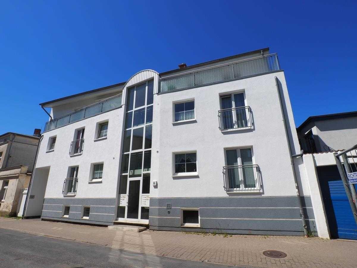Moderne, mehrstöckige Wohnung mit Balkonen und Glasfassade unter blauem Himmel.