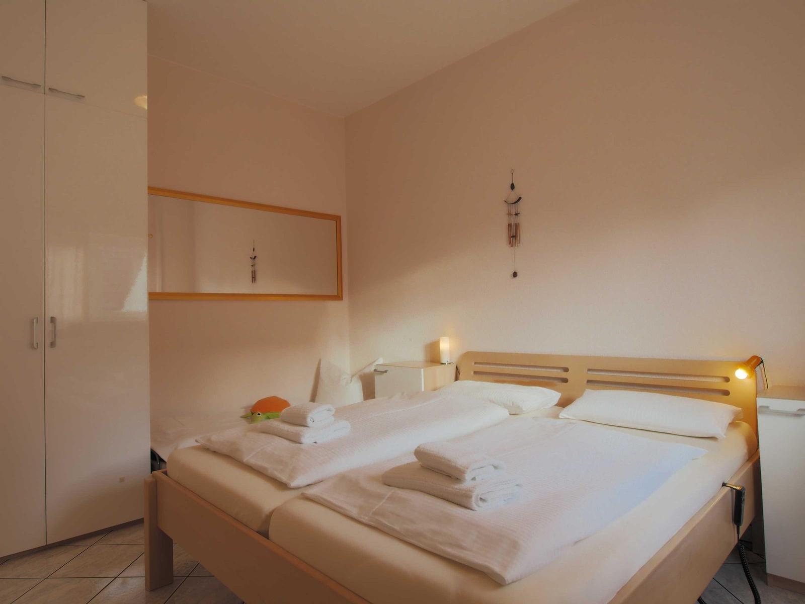 Schlafzimmer mit Bett, Kleiderschrank und Spiegel an der Wand.