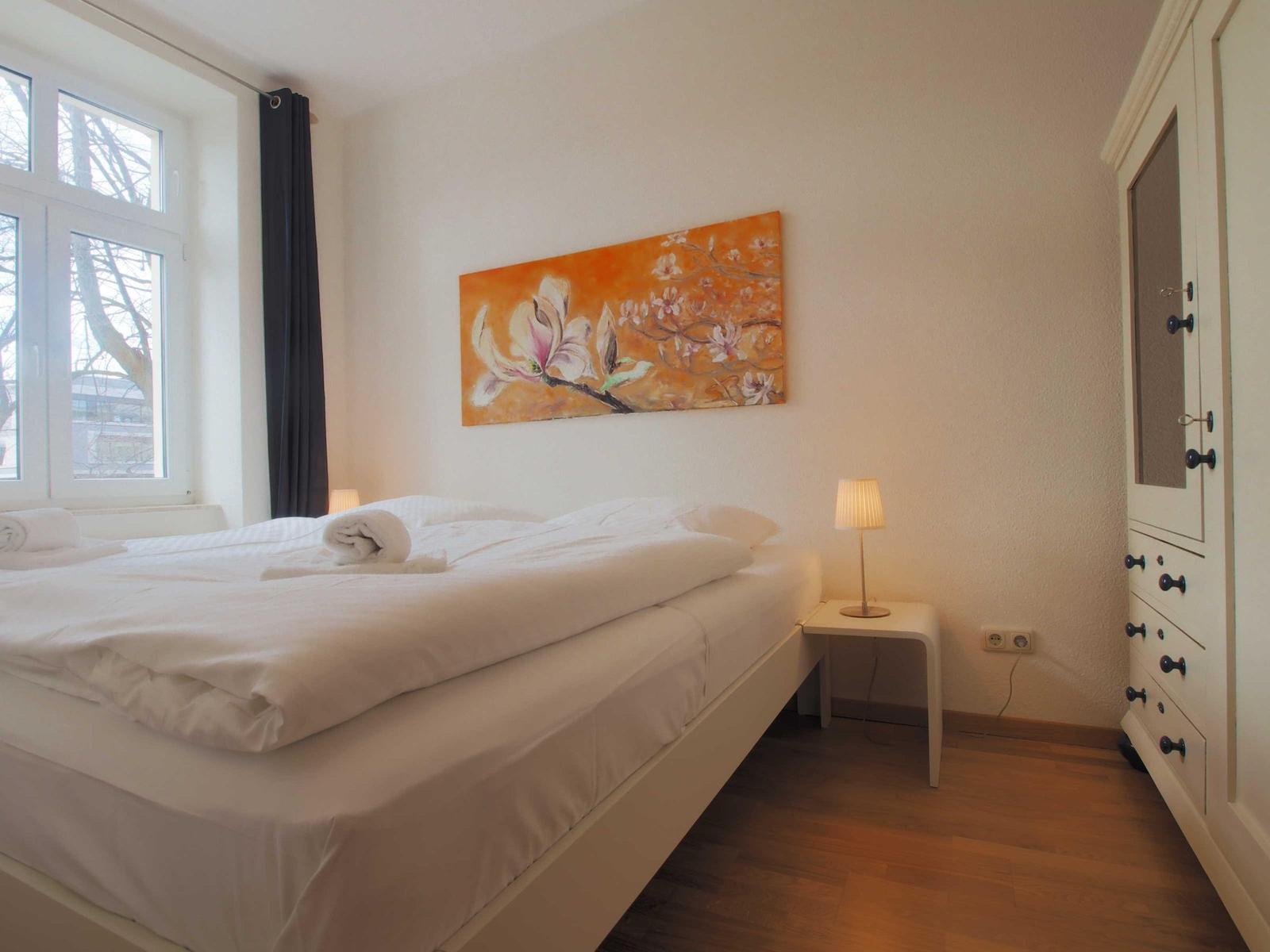 Schlafzimmer mit Bett, Nachttisch, Kleiderschrank und Wandbild