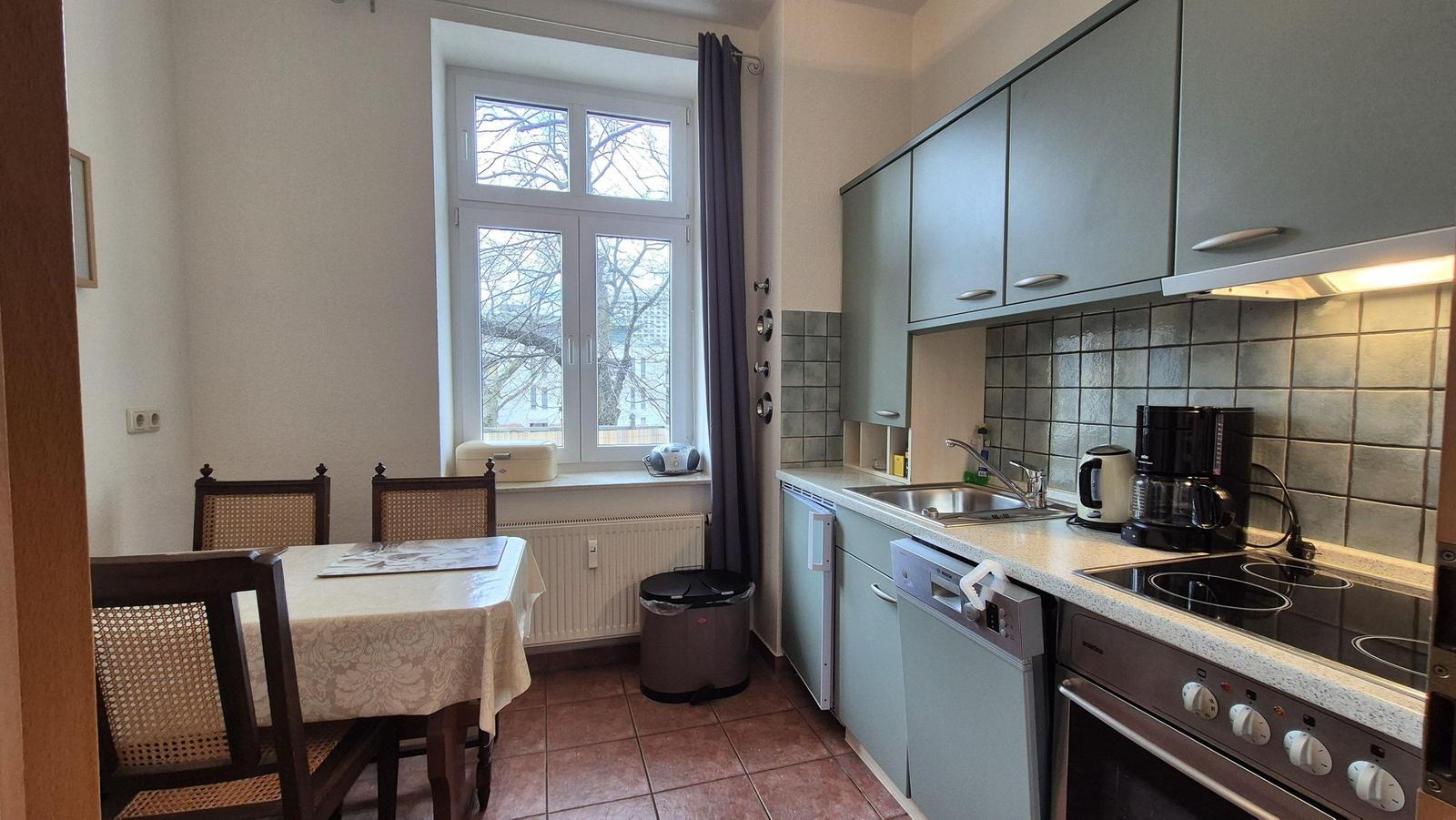 Küche mit Essbereich, Fenster, Spüle, Herd und Kühlschrank.