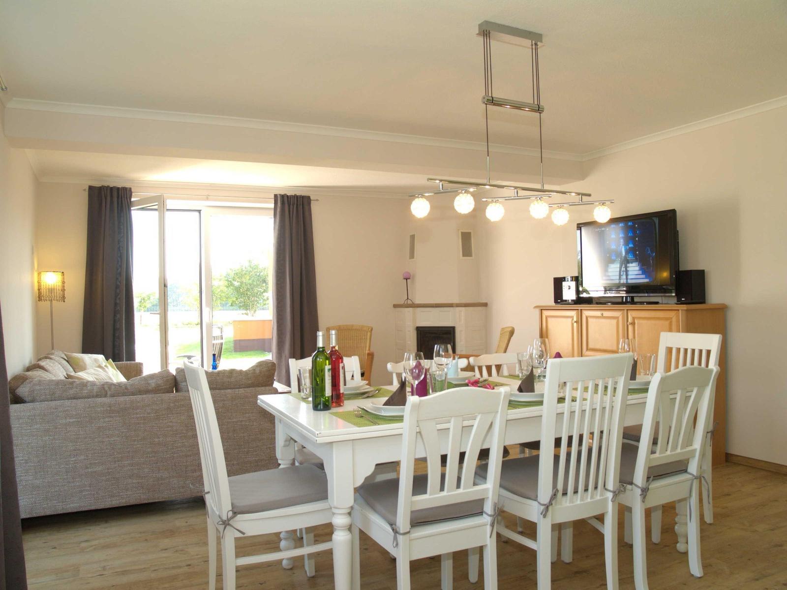 Esszimmer mit Tisch, Stühlen und Fernseher. Wohnbereich mit Sofa und Terrassentür.