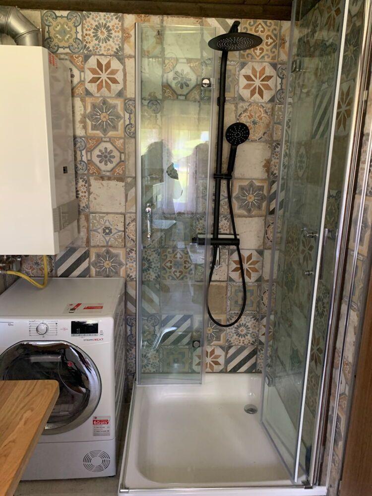 Shower cabin with glass enclosure and mosaic tiles on walls