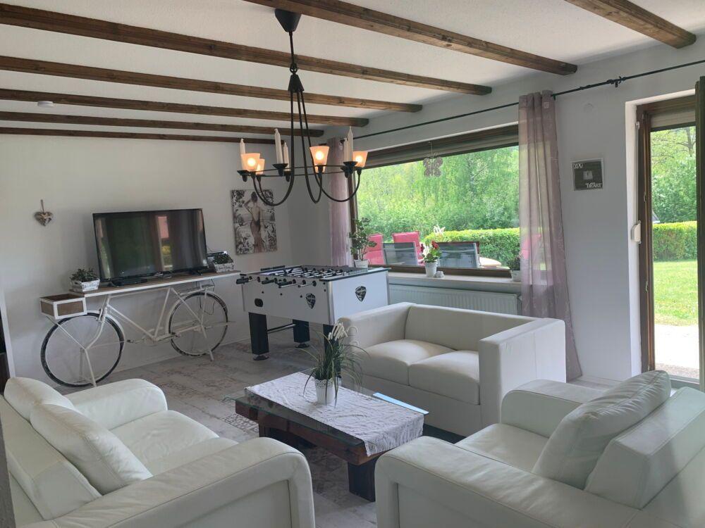 Living room with white sofas, foosball table, and bicycle against the wall.