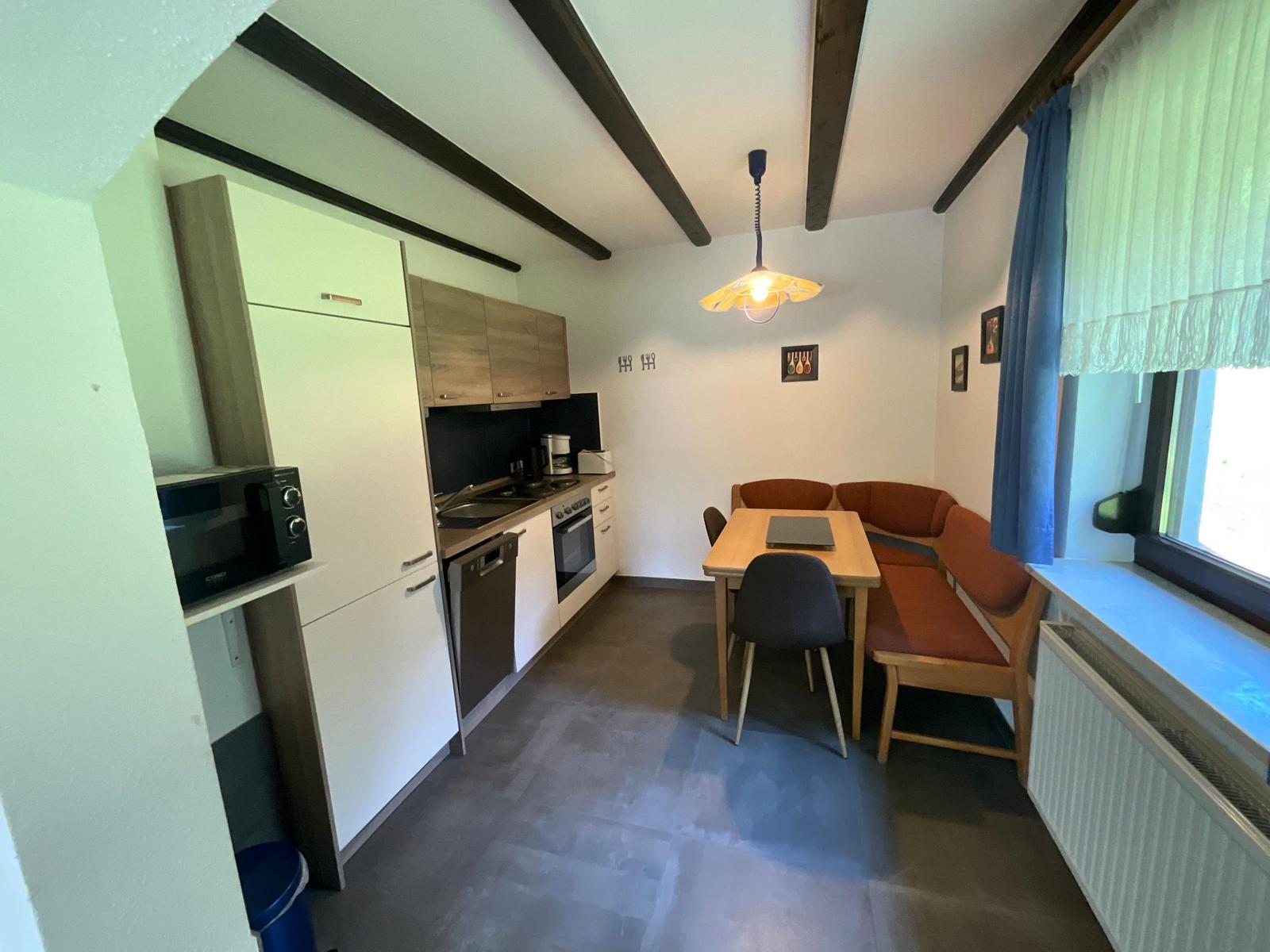 Kitchen with dining area, wooden bench, table and chairs under beams.
