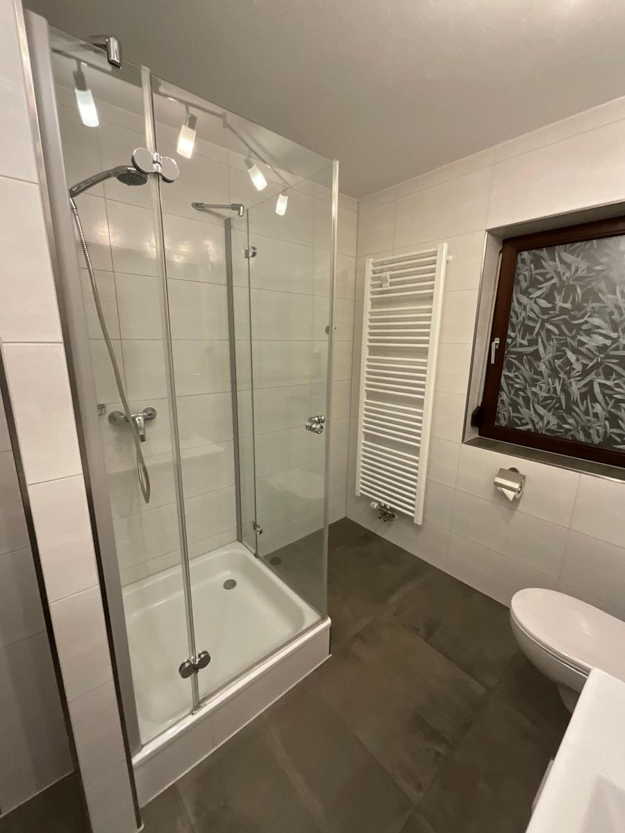 Bathroom with shower, heater, and toilet. Window with decorative glass.