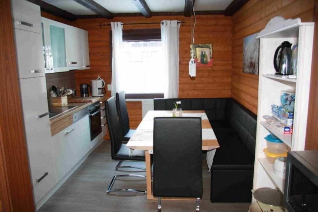 Kitchen with dining area and wooden walls. Table with chairs and sofa.