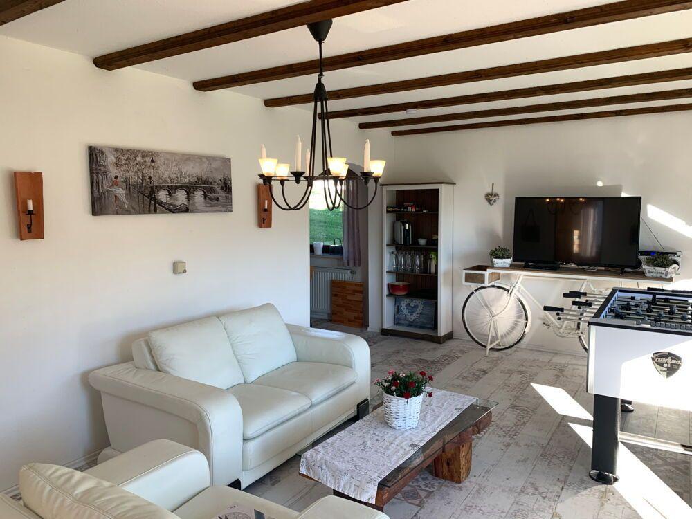 Living room with white sofa, table, and TV. Wooden beams on ceiling.