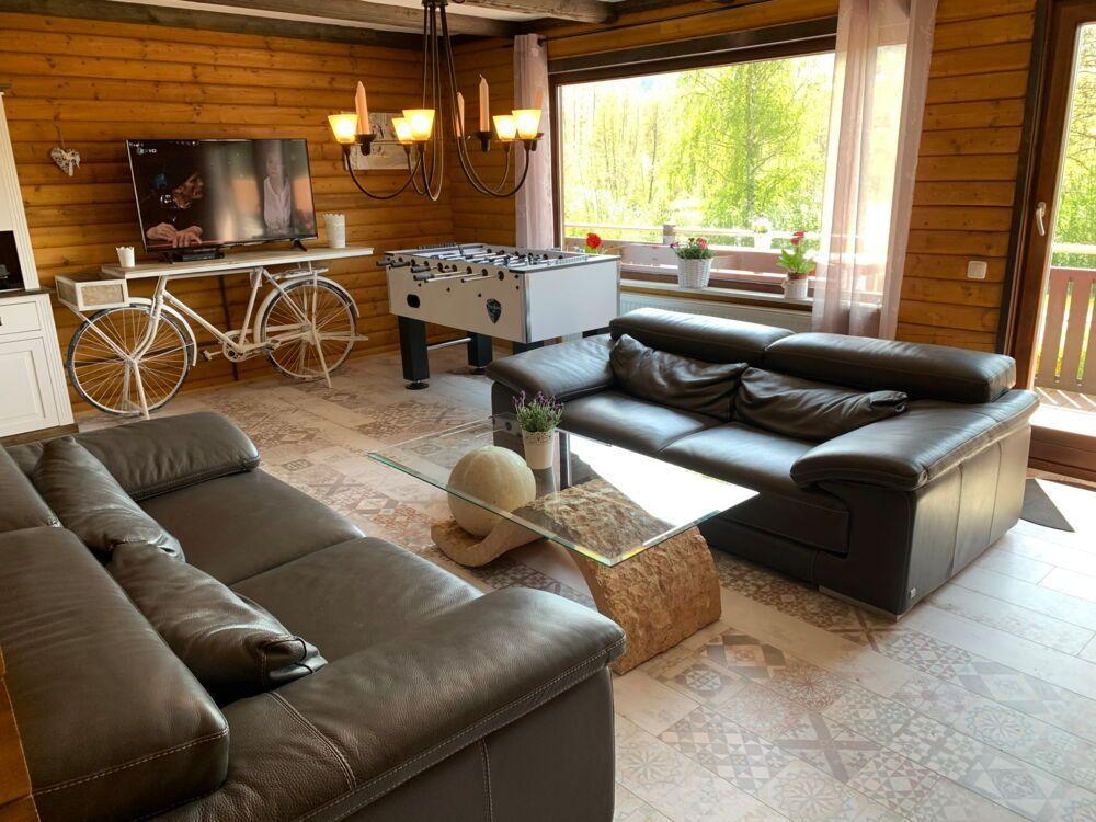 Living room with leather sofa, foosball table, and TV on wood wall.