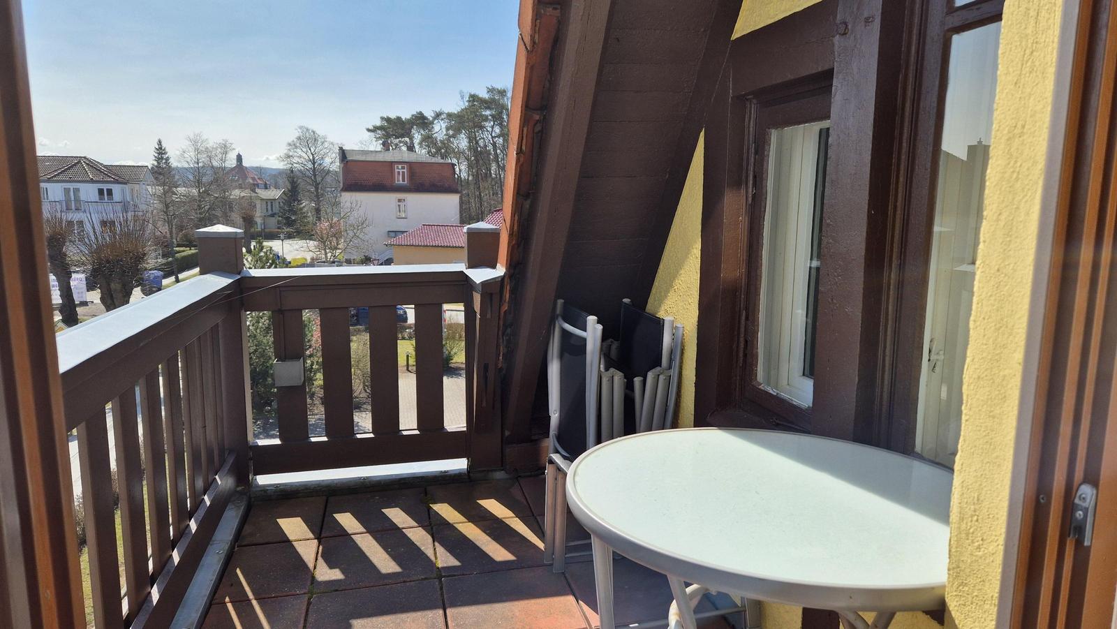 Terrasse mit Tisch und Stühlen, Blick auf Wohngebiet und Bäume.