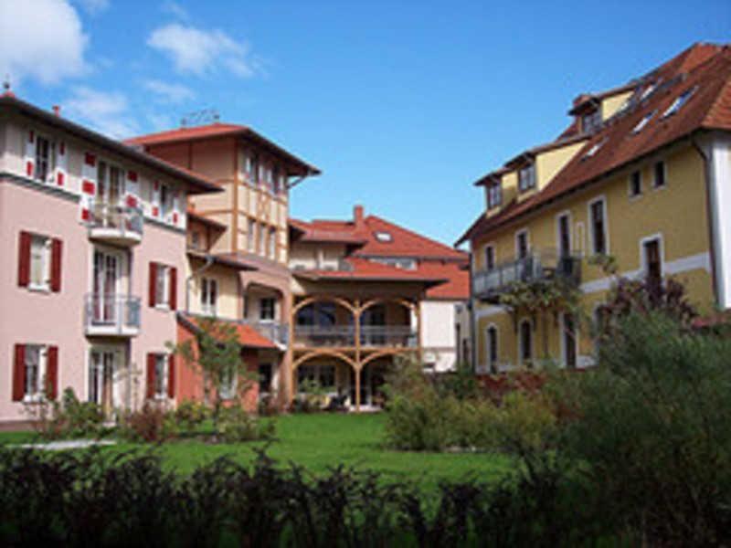 Haus mit Garten und Balkonen unter blauem Himmel
